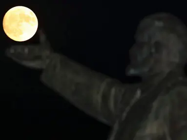 Supermoon terlihat di balik patung pendiri negara Soviet, Vladimir Lenin di Baikonur, Kazakhstan, (13/11). Fenomena ini merupakan bulan paling besar dan terang dalam kurun 70 tahun terakhir. (REUTERS/Shamil Zhumatov)