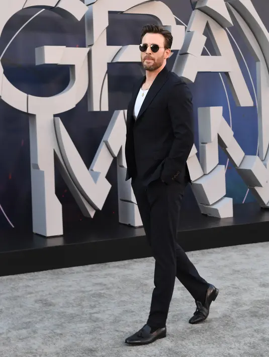 <p>Aktor Chris Evans menghadiri pemutaran perdana film The Grey Man di TCL Chinese Theatre, Hollywood, California, Amerika Serikat, 13 Juli 2022. Evans tampil keren dengan gaya kasual pada ansambelnya dan menyelipkan tee putih polos ke dalam celana panjang runcing. (VALERI MACON/AFP)</p>