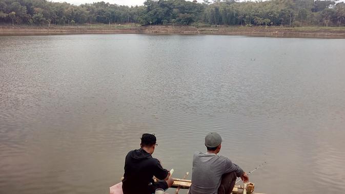 Dua warga sekitar, nampak asik melakukan mancing di area Situ Sarkanjut, Leuwigoong, Garut, Jawa Barat (Liputan6.com/Jayadi Supriadin)