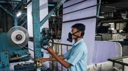 Kenaikan bahan baku ini memicu kekhawatiran akan peningkatan harga jual pakaian di tingkat konsumen, termasuk para pelaku bisnis fashion yang mulai merancang ulang strategi produk dan harga untuk bertahan. Situasi ini juga menuntut adaptasi cepat dari pelaku industri dalam negeri untuk mengelola rantai pasok yang tidak stabil dan biaya produksi yang tinggi. Tampak dalam foto, seorang pekerja mengoperasikan mesin di bagian pewarnaan kain di Trisula Textile Industries, Cimahi, Jawa Barat pada Rabu 22 April 2026, ketika para produsen tekstil menghadapi biaya yang lebih tinggi akibat melonjaknya harga bahan baku petrokimia yang terkait dengan kenaikan harga minyak global. (Timur MATAHARI/AFP)