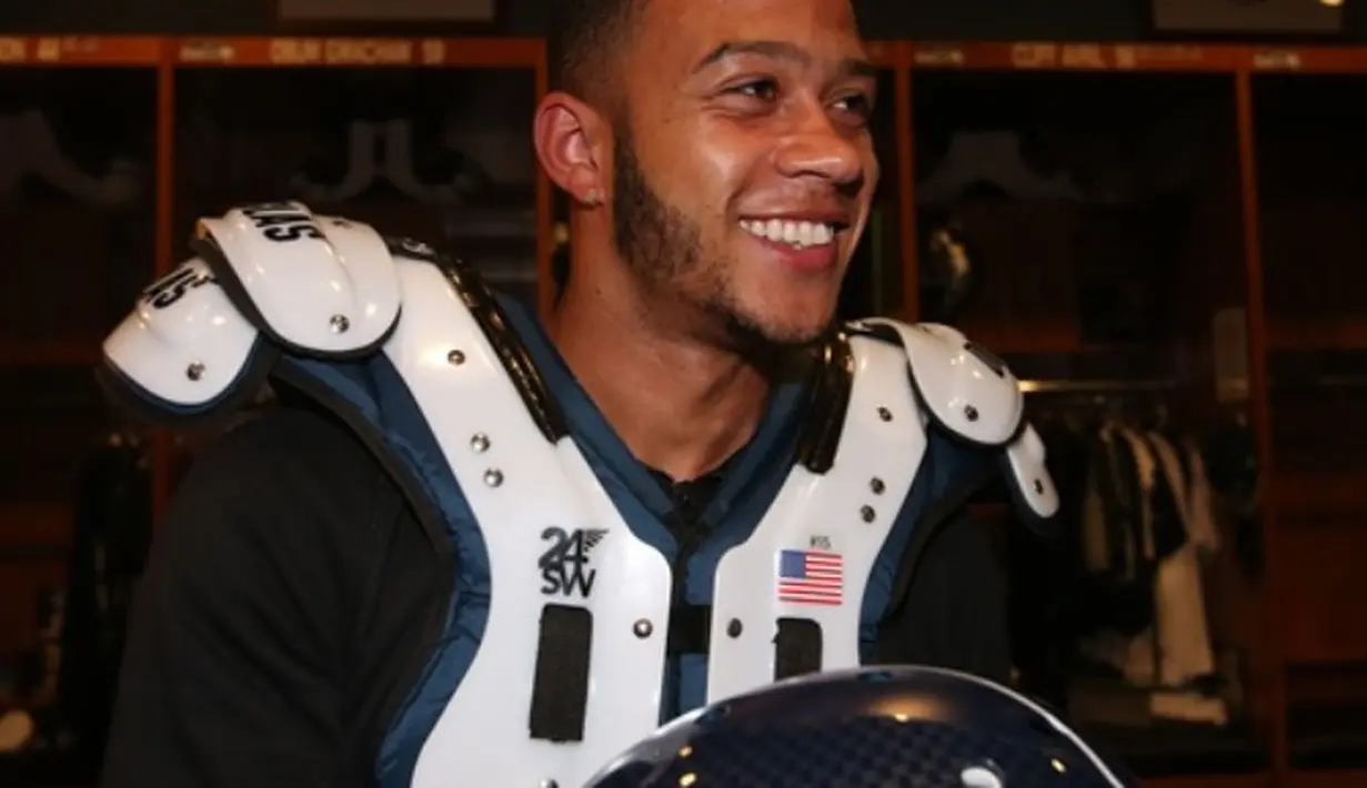 Memphis Depay mencoba perlengkapan American Football. (Manutd.com)