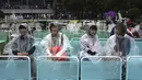 Penonton duduk saat hujan ketika permainan dihentikan di lapangan luar saat pertandingan tunggal putaran pertama mereka di kejuaraan tenis Australia Terbuka di Melbourne, Australia, Senin (20/1/2020). (AP Photo/Andy Brownbill)