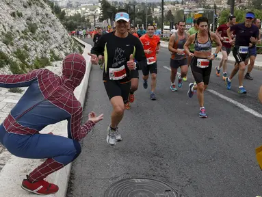 Seorang pria mengenakan kostum superhero Spiderman menggoda para atlet lari di kota tua, Yerusalem, Israel, (18/2).  Sejumlah orang mengikuti lomba lari Maraton Internasional  yang ke-6 di Yerusalem. (REUTERS / Baz Ratner)