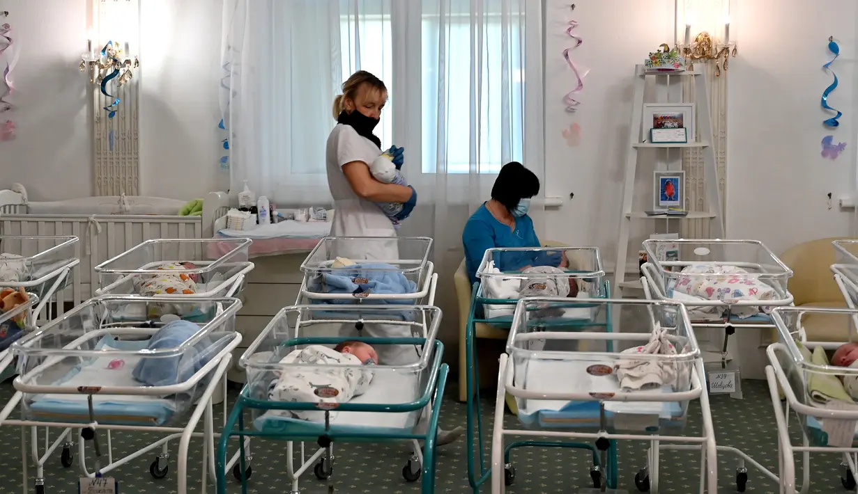 Perawat merawat bayi yang baru lahir dari skema ibu pengganti (surrogate mother) di Hotel Venice, Kiev, Ukraina, 15 Mei 2020. Bayi-bayi tersebut telantar karena orangtua mereka tidak dapat mengambil bayi-bayinya akibat lockdown selama pandemi virus corona COVID-19. (Sergei SUPINSKY/AFP)