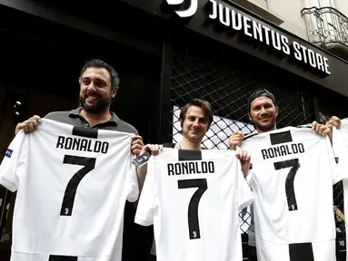 Suporter memperlihatkan jersey Juventus atas nama Cristiano Ronaldo di depan toko resmi klub di Turin, Selasa (10/7). Cristiano Ronaldo resmi pindah dari Real Madrid ke Juventus pada bursa transfer musim ini. (AFP PHOTO / Isabella Bonottovv)