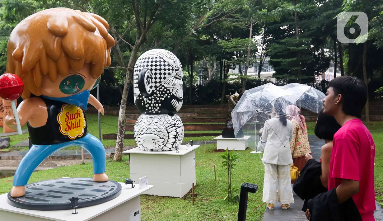 <p>Pengunjung melihat karya seni yang ditampilkan dalam pameran Art Jakarta Gardens 2023 di Hutan Kota Plataran, Senayan, Jakarta Pusat, Selasa (7/2/2023). Pameran seni Art Jakarta Gardens kembali digelar tahun ini mulai dari tanggal 7 - 12 Februari 2023, dalam pameran ini, pengunjung dapat menjelajahi kombinasi presentasi karya seni rupa yang ditampilkan dari dalam dan luar ruangan dengan karya berupa patung, instalasi, dan objek dua dimensi. (Liputan6.com/Herman Zakharia)</p>