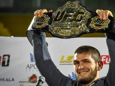 Foto pada 8 Oktober 2018, juara kelas ringan UFC Khabib Nurmagomedov dari Rusia mengangkat sabuk juara setibanya di Makhachkala. Khabib Nurmagomedov mengumumkan pensiun dari dunia seni bela diri campuran (MMA) seusai mengalahkan Justin Gaethje dalam UFC 254, Minggu (25/10/2020). (Vasily MAXIMOV/AFP)