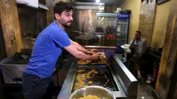 Seorang warga Suriah bekerja di sebuah rumah makan di daerah bernama kota 6 Oktober, Giza, Mesir, (19/3). Rata - rata penjual makanan di tempat ini menjual makanan khas Suriah. (REUTERS / Mohamed Abd El Ghany)