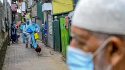 Petugas kesehatan tentara berjalan melalui gang saat melakukan vaksinasi virus corona COVID-19 untuk penduduk sebuah wilayah di Kolombo, Sri Lanka, Kamis (12/8/2021). (Ishara S. KODIKARA/AFP)