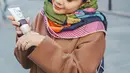 Nagita Slavina tampil chic dalam balutan coat cokelat, sling bag cokelat yang serasi, dan ia melingkarkan syal bermotif abstrak berbagai warna yang meriah. [Foto: Instagram/raffinagita1717]