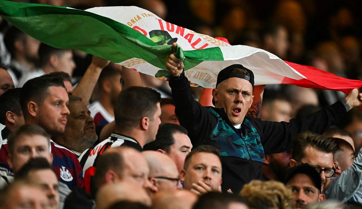 Seorang pendukung membentangkan bendera Italia saat Sandro Tonali melakukan comeback bersama Newcastle pada laga Carabao Cup 2024/2025 melawan Nottingham Forest di City Ground, Nottingham, Inggris, Kamis (29/08/2024) WIB. (AFP/Paul Ellis)