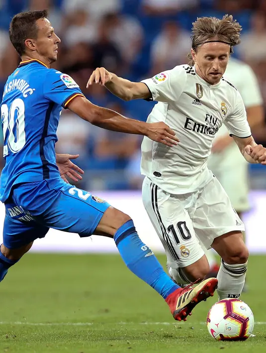 Gelandang Real Madrid, Luca Modric berusaha melewati pemain Getafe, Nemanja Maksimovic saat bertanding pada lanjutan La Liga Spanyol di stadion Santiago Bernabeu, Madrid, (19/8). Madrid menang 2-0 atas Getafe. (AP Photo/Andrea Comas)