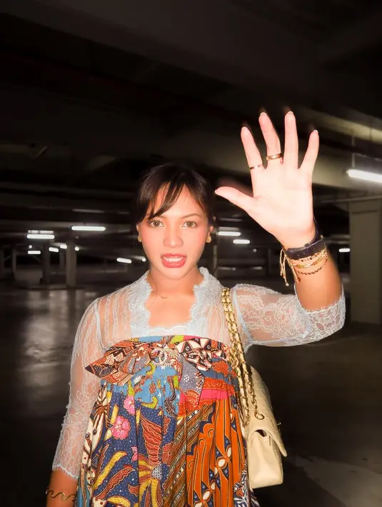 Aksesori yang dikenakan pun memperkuat gaya eklektik ini. Tumpukan gelang emas, cincin emas minimalis, dan tas rantai berwarna krem menjadi aksen modern yang menyeimbangkan nuansa tradisional dari busananya.  [@amelcarla].