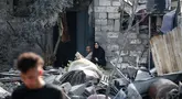 Warga Palestina duduk di antara reruntuhan rumah setelah serangan Israel semalam yang menghantam Nuseirat, Jalur Gaza tengah pada 13 Juli 2025. (Eyad BABA/AFP)