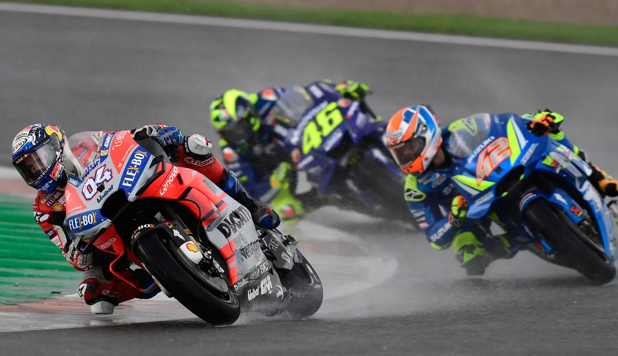Pebalap Ducati, Andrea Dovizioso (kiri) disusul pebalap Movistar Yamaha, Valentino Rossi dan pebalap Suzuki, Alex Rins saat balapan MotoGP Grand Prix Valencia di arena balapan Ricardo Tormo, Cheste, Minggu (18/11). (Jose Jordan/AFP)