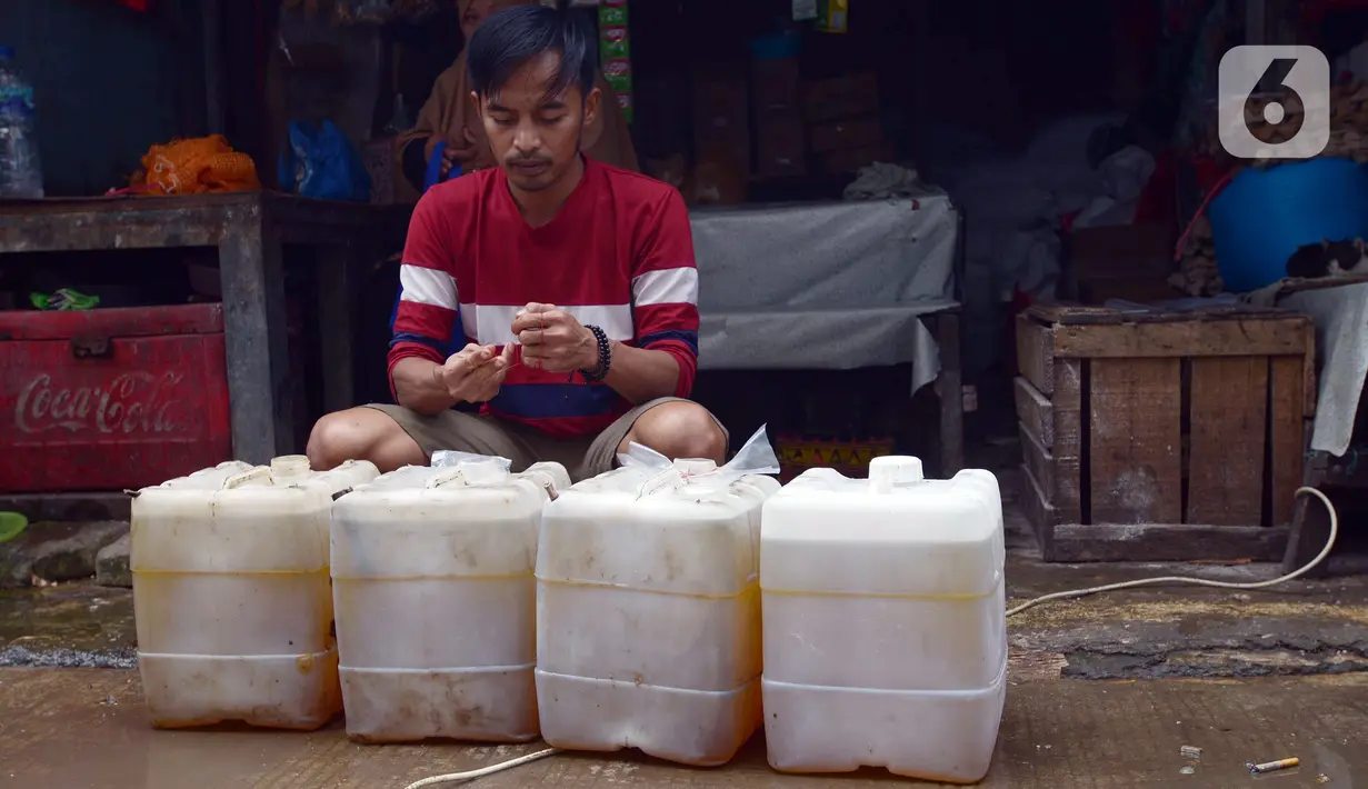 Seorang pria berada dekat deretan jeriken berisi minyak goreng curah di Pasar Perumnas, Jumat (25/2/2022). Langkah cepat dalam mengisi pasokan ke pasar-pasar diharapkan bisa menstabilkan harga minyak goreng curah yang ditetapkan pemerintah sebesar Rp 11.500 per liter. (merdeka.com/Imam Buhori)