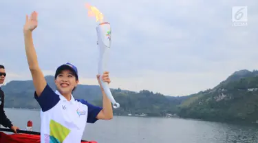 Artis Olivia Zalianty membawa obor Asian Games 2018 berkeliling Danau Toba di Sumatra Utara, Rabu (1/8). Obor Asian Games itu akan di bawa berlayar dengan kapal hias di Danau Toba dan bersepeda menuju pantai bebas Danau Toba. (Liputan6.com/Reza Perdana)