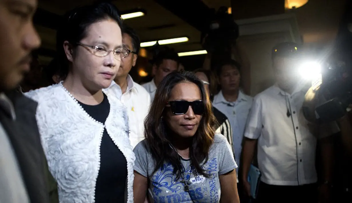 Maria Kristina Sergio (berkacamata hitam), perekrut terpidana mati Mary Jane dikawal petugas usai melakukan konferensi persi di Markas Polisi Camp Crame, kota Quezon, Filipina, Rabu (29/4/2015). (AFP PHOTO/NOEL CELIS)