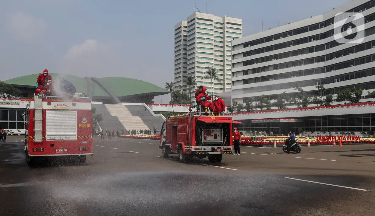 Petugas pemadam kebakaran menyemprotkan cairan disinfektan di Kompleks Parlemen, Senayan, Jakarta, Minggu (9/8/2020). Penyemprotan cairan disinfektan tersebut dilakukan dalam rangka pencegahan penyebaran virus Corona (COVID-19) di lingkungan DPR/MPR. (Liputan6.com/Johan Tallo)