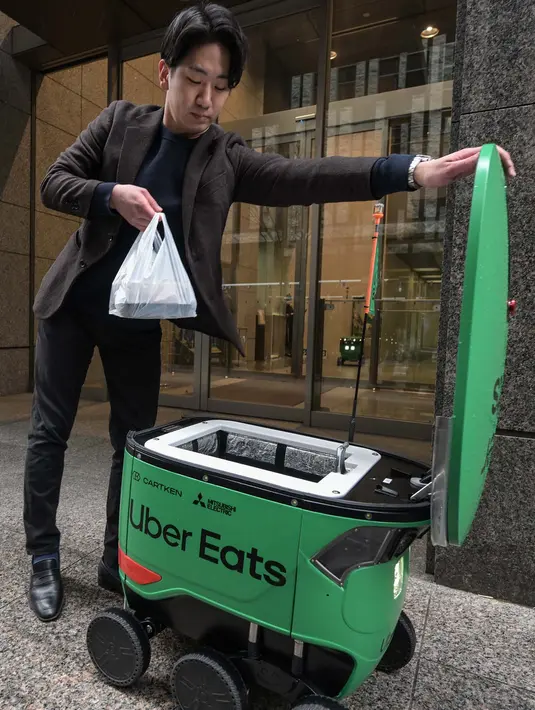 <p>Robot-robot berbentuk kotak milik Uber Eats memiliki lampu depan berbentuk kotak sebagai mata dan tiga roda di setiap sisinya untuk menavigasi trotoar. (Richard A. Brooks/AFP)</p>