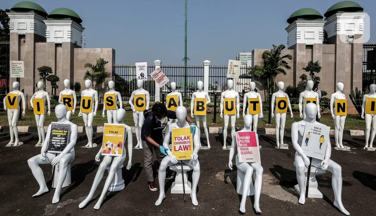Aktivis Greenpeace Indonesia menata puluhan maneken saat menggelar aksi damai di depan gerbang kompleks DPR, Jakarta Pusat, Senin (29/6/2020). Aksi tersebut dilakukan sebagai bentuk penolakan terhadap RUU Omnibus Law. (Liputan6.com/Johan Tallo)