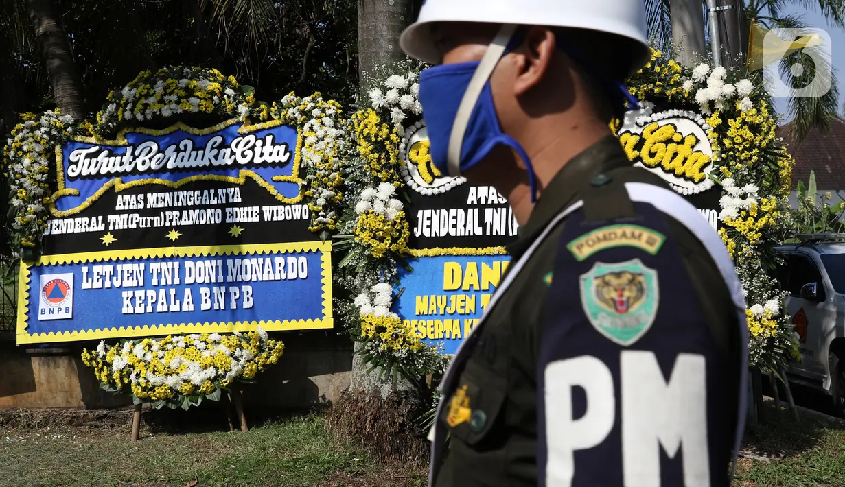 Prajurit TNI melintas di depan karangan bunga tanda duka cita atas meninggalnya mantan KSAD Jenderal TNI (Purn) Pramono Edhie Wibowo di kawasan Puri Cikeas, Kab Bogor, Jabar, Minggu (14/6/2020). Pramono Edhie Wibowo wafat di usia 65 tahun akibat serangan jantung. (Liputan6.com/Helmi Fithriansyah)
