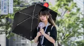 Seorang wanita menggunakan payung untuk berlindung dari sinar matahari saat berjalan di sepanjang jalan di Tokyo pada 19 September 2024. (Yuichi YAMAZAKI/AFP)