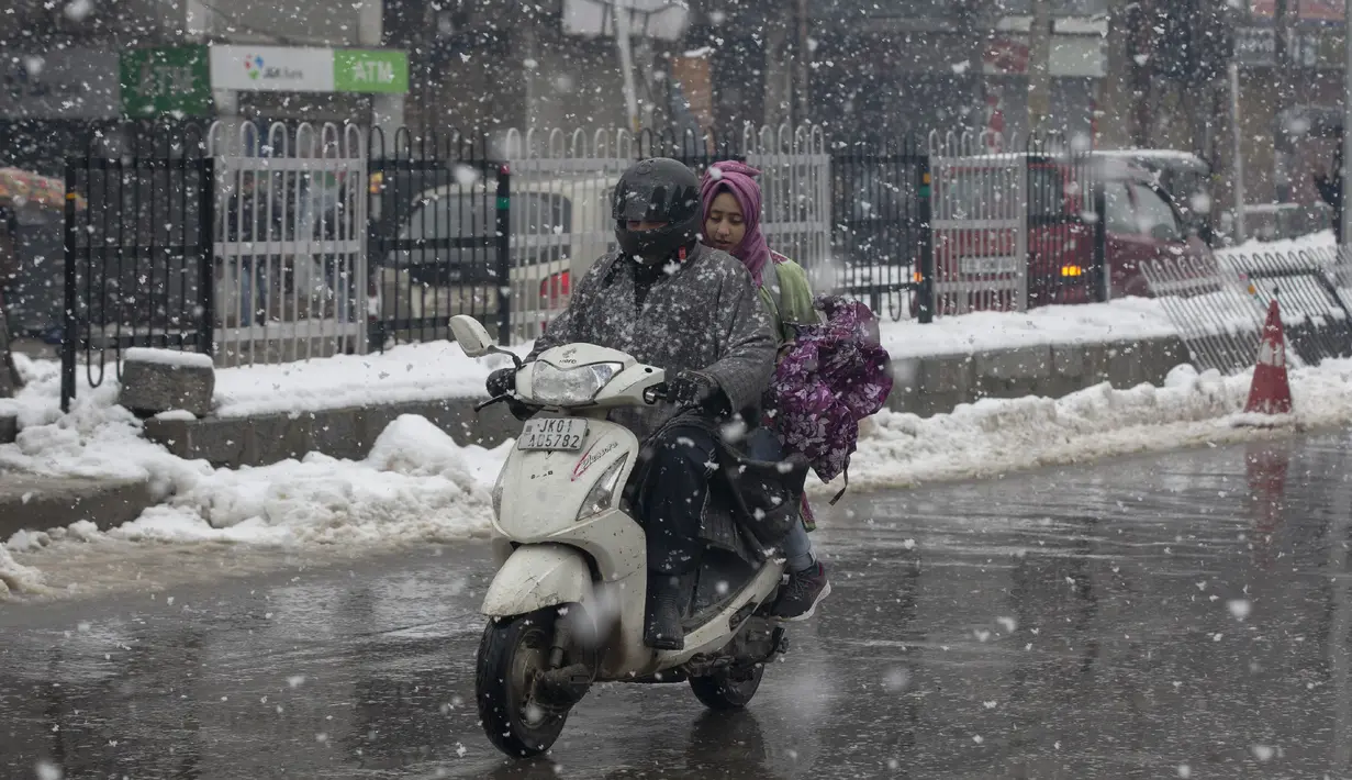 Seorang pria Kashmir mengendarai skuter saat salju turun di Srinagar, Kashmir yang dikuasai India (15/1/2020). Selama dua hari terakhir wilayah Himalaya telah menyaksikan hujan salju lebat yang mengakibatkan serangkaian longsoran dan tanah longsor. (AP Photo/Dar Yasin)