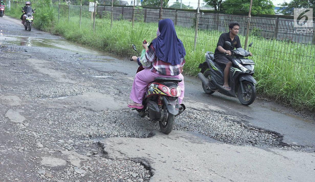Pengendara sepeda motor melintasi jalan yang rusak di Jalan Raya Gas Alam, Depok, Jawa Barat, Selasa (7/5). Kondisi jalan yang tidak kunjung diperbaiki tersebut menjadi kubangan air setiap hujan serta berbahaya bagi keselamatan pengguna jalan. (Liputan6.com/Immanuel Antonius)