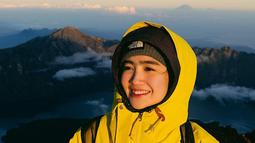 Secerah senyumannya, Febb Rastanty mengenakan jaket kuning saat mendaki Rinjani. (Foto: Instagram/ febbyrastanty)
