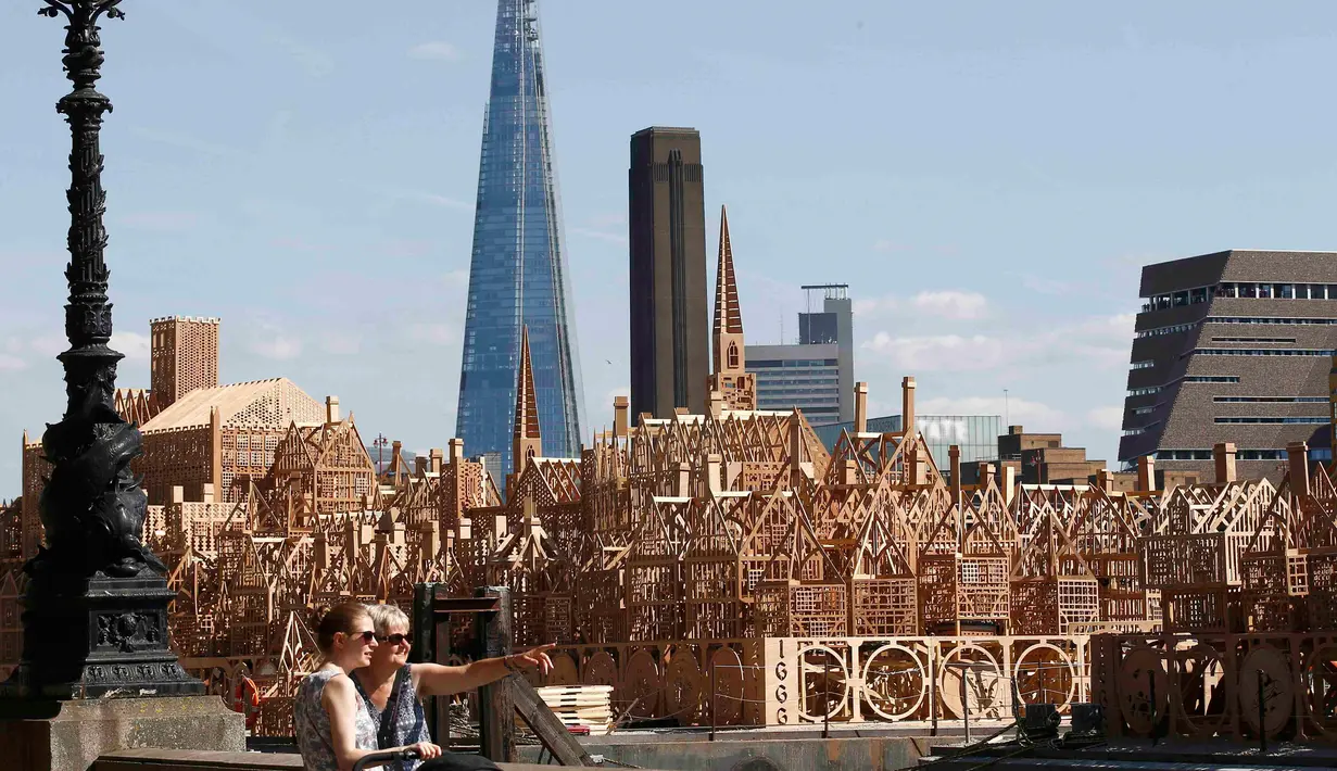 Pejalan kaki melintas di dekat patung skyline Kota London sepanjang 120 meter di London, Inggris, (30/8). Patung ini akan dibakar dalam sebuah acara untuk mengenang bencana Kebakaran besar London pada 1666. (REUTERS/Peter Nicholls)