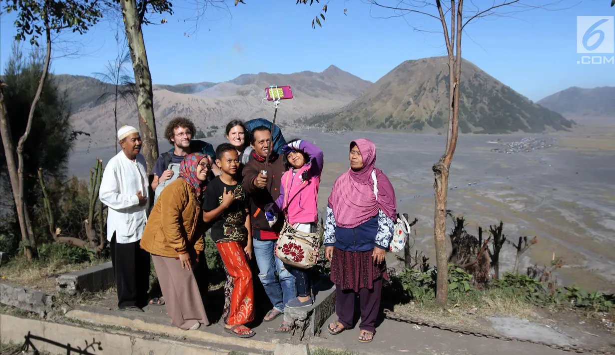 Wisatawan domestik berswafoto dengan turis asing di Taman Nasional Bromo Tengger Semeru, Probolinggo, Jawa Timur, Minggu (8/7). Bromo masih menjadi destinasi wisata primadona yang ramai dikunjungi wisatawan setiap tahunnya. (Liputan6.com/Arya Manggala)