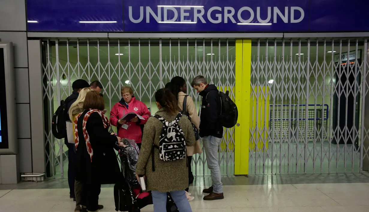 Calon penumpang menunggu di luar stasiun kereta bawah tanah Cannon Street yang tutup di London, Senin (9/1). Ratusan warga London terlantar dan kesulitan berpergian akibat mogok kerja yang dilakukan oleh staf kereta bawah tanah. (AP Photo/Matt Dunham)