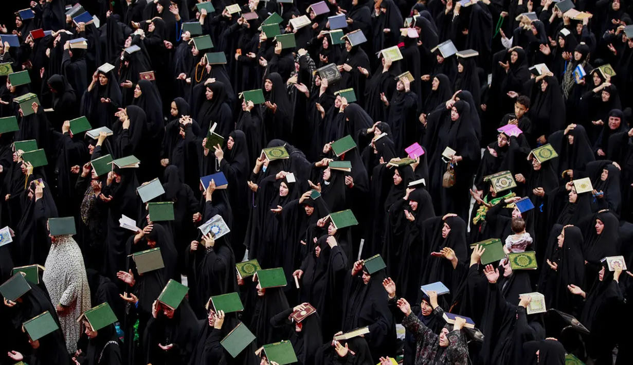 <p>Dalam ritual ini, umat Syiah melakukan ritual dengan menempatkan salinan Alquran di atas kepala mereka. (AP Photo/Anmar Khalil)</p>