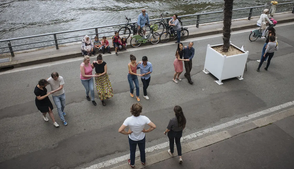 Orang-orang menari di tepi Sungai Seine, Paris, Prancis, Minggu (11/7/2021). Prancis telah mengakhiri kewajiban mengenakan masker di luar ruangan dan pencabutan jam malam sejak pertengahan Juni lalu menyusul penurunan kasus COVID-19. (AP Photo/Lewis Joly)