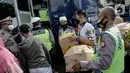 Polisi membantu membawakan barang penumpang yang terjaring razia travel gelap Ditlantas Polda Metro Jaya saat akan dipulangkan ke daerah asalnya, Jakarta, Kamis (29/4/2021). Sebanyak 115 kendaraan travel gelap diamankan. (Liputan6.com/Faizal Fanani)
