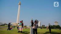 Beberapa remaja berswafoto berlatar Monumen Nasional (Monas), Jakarta, Kamis (8/2/2024). (Liputan6.com/Angga Yuniar)