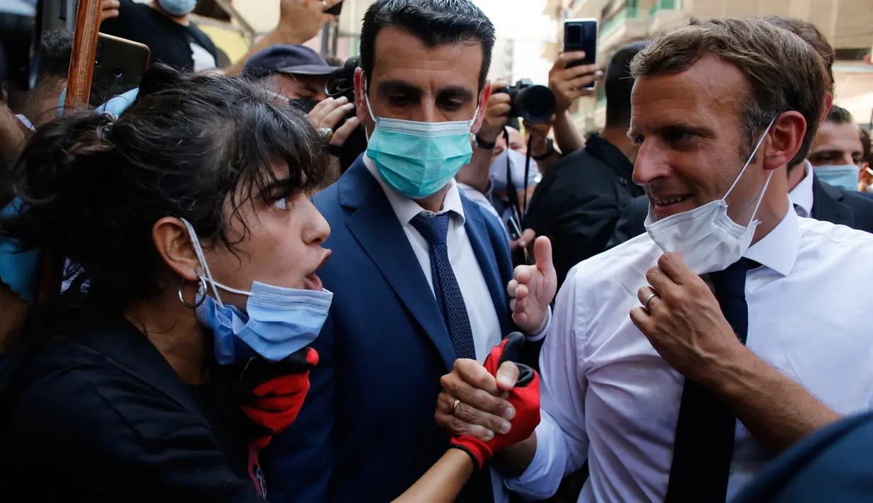 Presiden Prancis Emmanuel Macron mendengarkan warga saat mengunjungi lokasi ledakan di Beirut, Lebanon, Kamis (6/8/2020). Presiden Macron menjadi pemimpin dunia pertama yang mengunjungi Lebanon, usai ledakan besar menghancurkan Beirut pada Selasa (4/8) lalu.. (AP Photo/Thibault Camus, Pool)