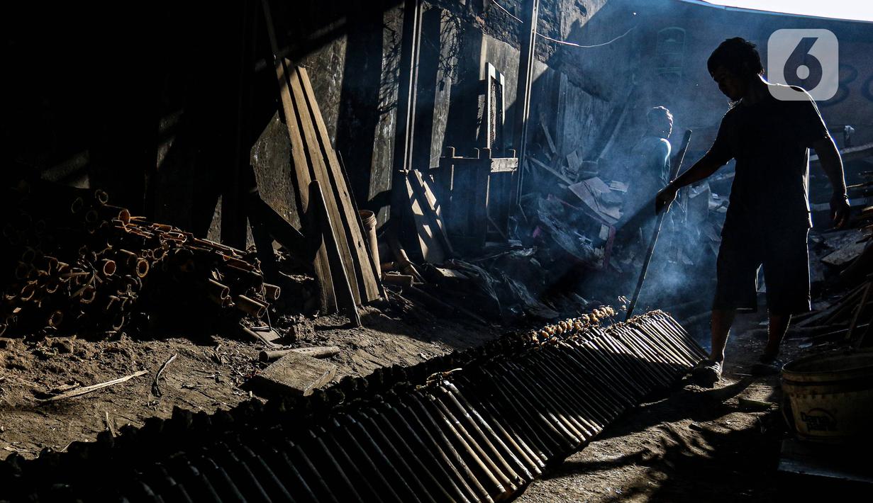 Pekerja melakukan pembakaran lemang bambu di Jalan Kramat Raya, Senen, Jakarta Pusat, Rabu (6/4/2022). Makanan khas Sumatera Barat yang cocok dijadikan sebagai menu berbuka puasa tersebut dijual dengan harga Rp 15.000 - Rp 30.000. (Liputan6.com/Herman Zakharia)