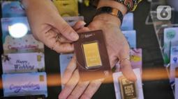 Pegawai menunjukkan emas batangan di Galeri 24, Jakarta, Selasa (13/9/2022). Harga jual kembali (buyback) emas Antam ikut naik Rp 3.000, dibanderol Rp 823.000 per gram. (Liputan6.com/Angga Yuniar)