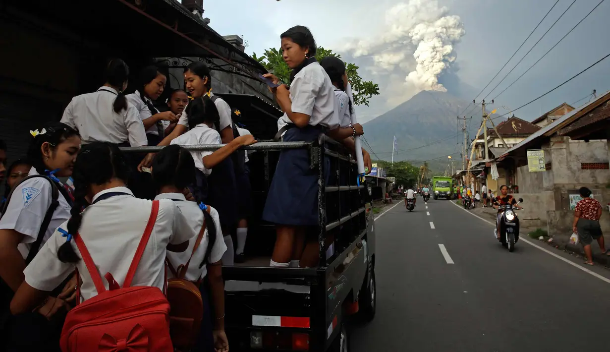 Pelajar bersiap berangkat ke sekolah menggunakan mobil saat erupsi Gunung Agung di Karangasem, Bali, (28/11). Pihak berwenang memberi peringatan kepada warga untuk mengungsi akibat stasus Gunung Agung yang dari siaga ke awas. (AP Photo/Firdia Lisnawati)