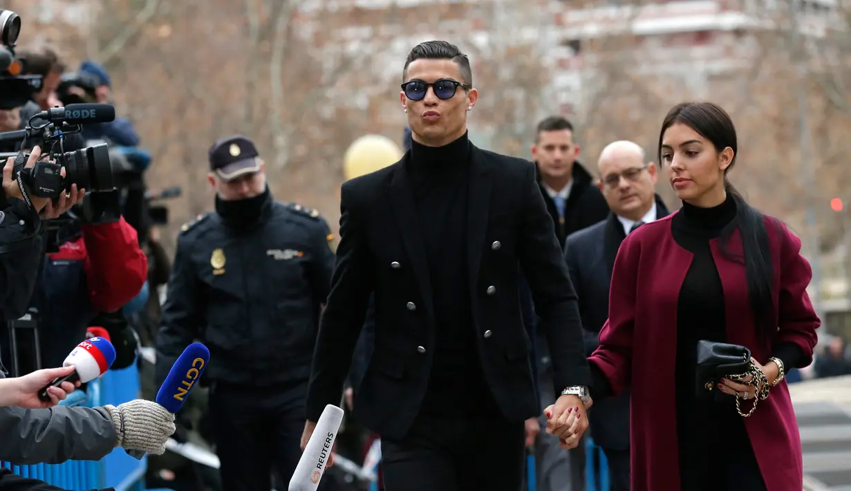 Pemain Juventus Cristiano Ronaldo menggandeng kekasihnya Georgina Rodriguez saat tiba di pengadilan di Kota Madrid, Spanyol, Selasa (22/1). Ronaldo mengikuti sidang dugaan penggelapan pajak. (AP Photo/Manu Fernandez)