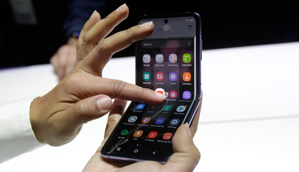 Seorang pekerja Samsung mendemonstrasi Galaxy Z Flip pada acara Unpacked 2020 di San Francisco, Selasa (11/2/2020). Menjadi perangkat kedua dengan layar lipat karyanya, Samsung menghadirkan perbedaan desain pada Galaxy Z Flip jika dibandingkan ponsel generasi pertama, Galaxy Fold. (AP/Jeff Chiu)