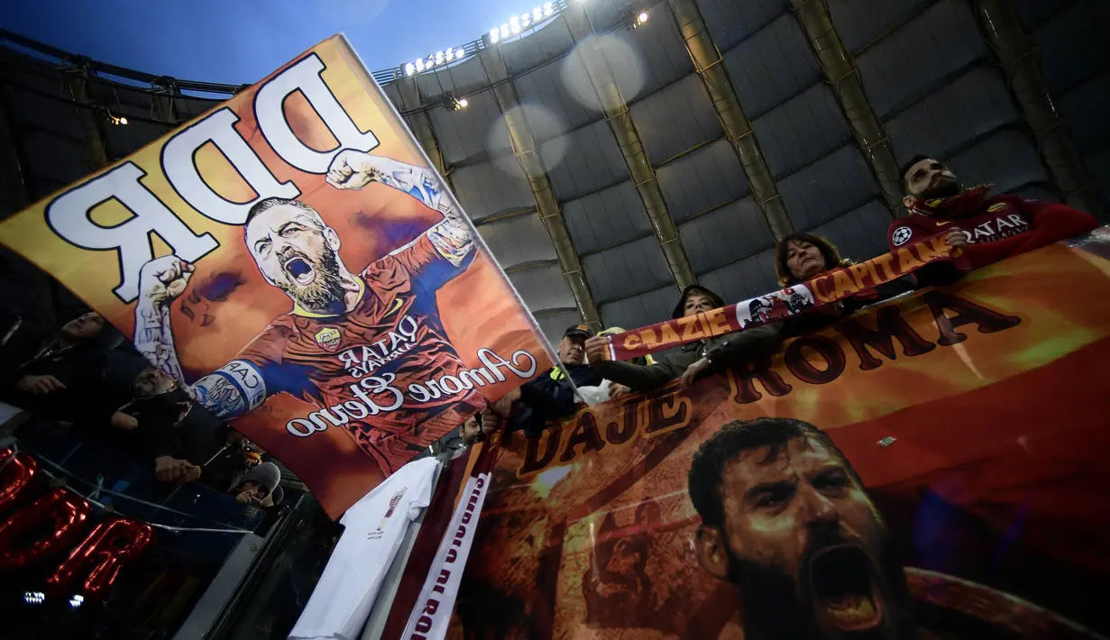 Suporter mengibarkan bendera bergambar gelandang AS Roma, Daniele De Rossi saat melawan Parma pada laga Serie A di Stadion Olympic, Roma, Minggu (26/5). Laga ini perpisahan bagi De Rossi dan AS Roma setelah 18 tahun. (AFP/Filippo Monteforte)