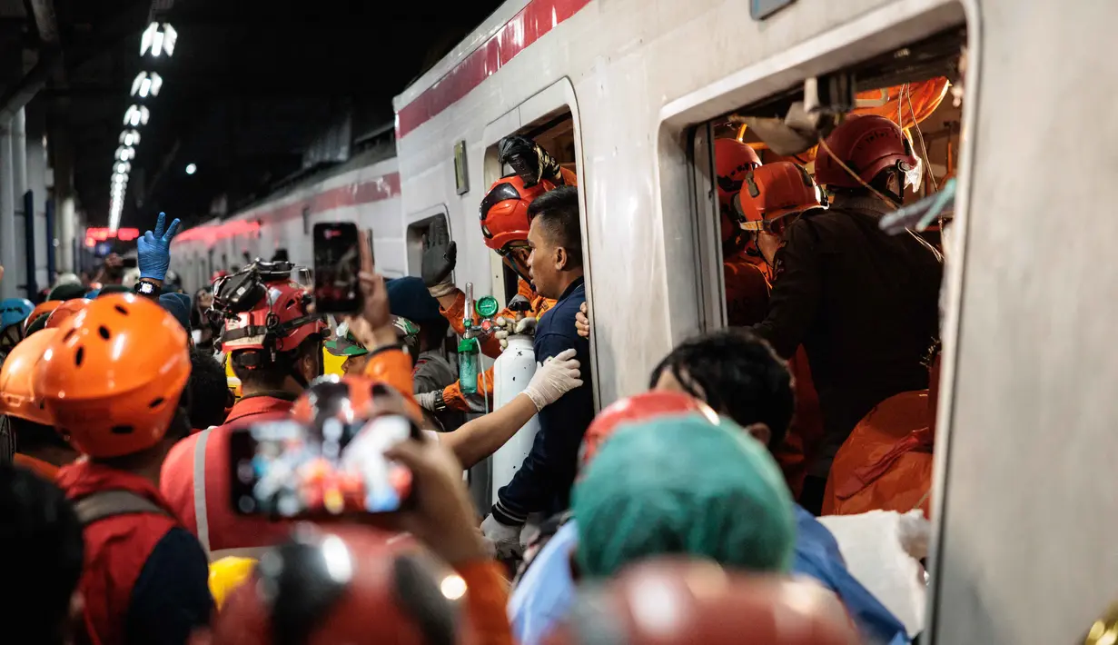 Tim pencari dan penyelamat gabungan berupaya menyelamatkan salah satu korban yang terjebak di dalam gerbong setelah lokomotif Kereta Api Jarak Jauh (KAJJ) Argo Bromo Anggrek menabrak gerbong belakang Kereta Rel Listrik (KRL) Commuter Line di stasiun Bekasi Timur, Bekasi, Jawa Barat pada Selasa 28 April 2026. (Yasuyoshi Chiba/AFP)