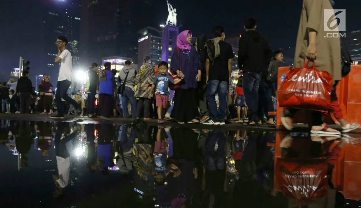 Warga memadati malam pergantian tahun di kawasan Bundaran HI, Jakarta, Minggu (31/12). Pemprov DKI Jakarta memberlakukan car free night di Jalan Sudirman hingga Thamrin. (Liputan6.com/Angga Yuniar)