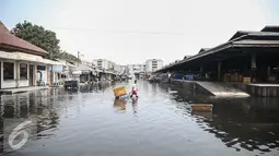 Warga melintasi genangan banjir di pasar ikan Pelabuhan Muara Baru, Penjaringan, Jakarta, (7/6). Banjir rob terjadi akibat jebolnya tanggul di sisi Timur Pelabuhan Muara Baru hingga meluapnya air yang mencapai sekitar 50 cm. (Liputan6.com/Faizal Fanani)