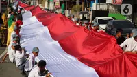 Pelajar SMA membentangkan bendera Merah Putih sepanjang 2,3 kilometer di Jalan Panjaitan dan Jalan Nani Wartabone, Gorontalo, Kamis (23/1/2020). Para pelajar menyanyikan lagu Indonesia Raya sambil membentangkan bendera Merah Putih. (Liputan6.com/Arfandi Ibrahim)