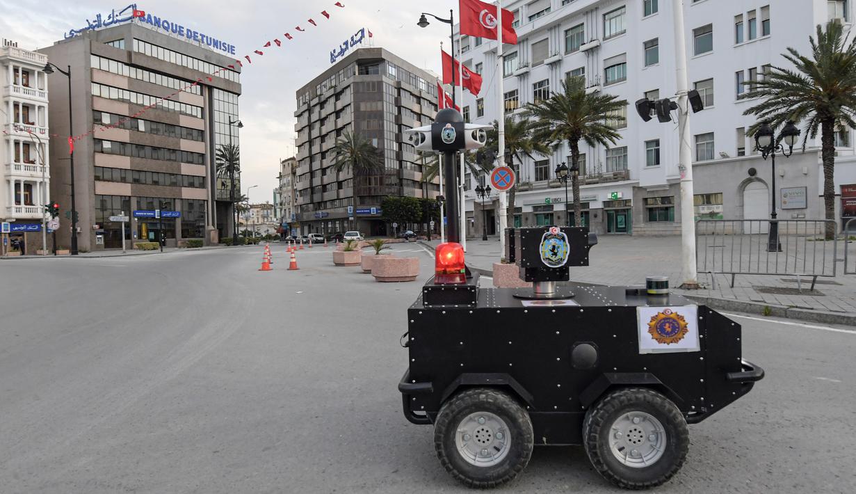 Robot polisi Tunisia berpatroli selama kebijakan penguncian (lockdown) di sepanjang Avenue Habib Bourguiba, pusat ibu kota Tunis, Rabu (1/4/2020). Selain untuk pengawasan dan pemberian sanksi, robot ini juga digunakan memberikan pesan agar warga Tunisia tetap berada di rumah. (FETHI BELAID/AFP)