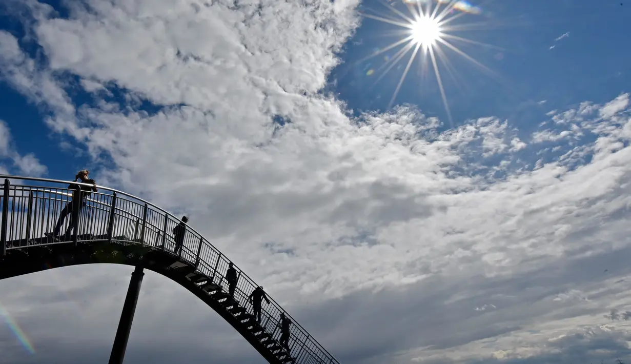 Orang-orang berjalan di sebuah instalasi tangga melingkar "Tiger and Turtle" di Duisburg, 30 April 2018. Jalan setapak menyerupai roller coaster dengan tinggi 21 meter ini dibangun oleh seniman Jerman, Heike Mutter dan Ulrich Genth. (AP/Martin Meissner)